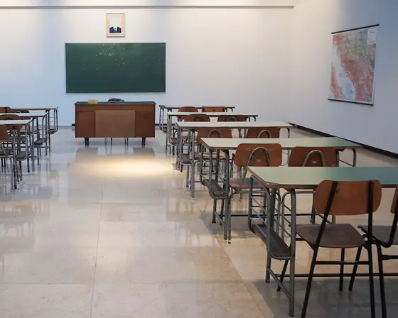 Empty classroom with desks and a blackboard.